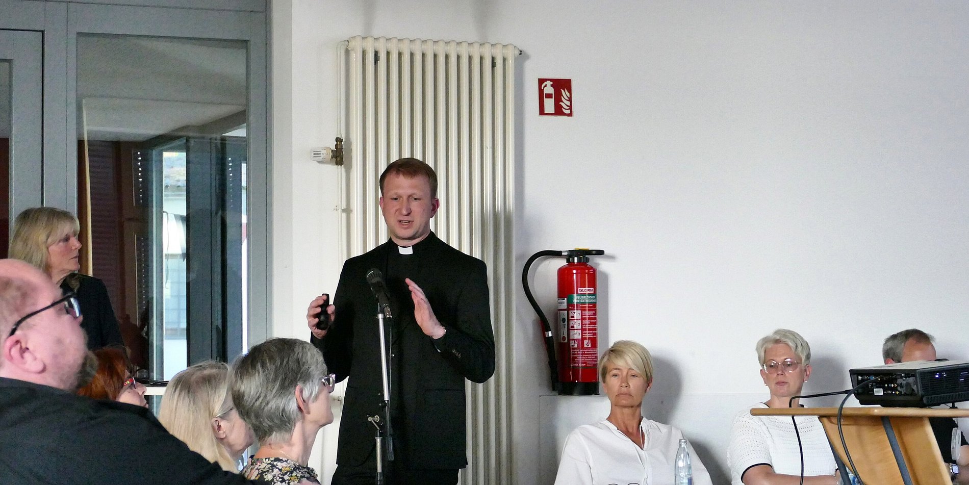 Bild von Pfarrer Benedikt Wach, wie er den Teilnehmenden das zukünftige Gebäudekonzept vorstellt.