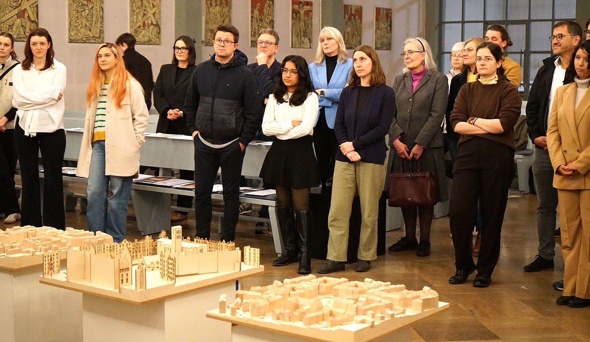 Im Vordergrund sind die Modelle zu sehen, dahinter steht das Publikum und blickt auf die Redner, die sich außerhalb des Fotos befinden.