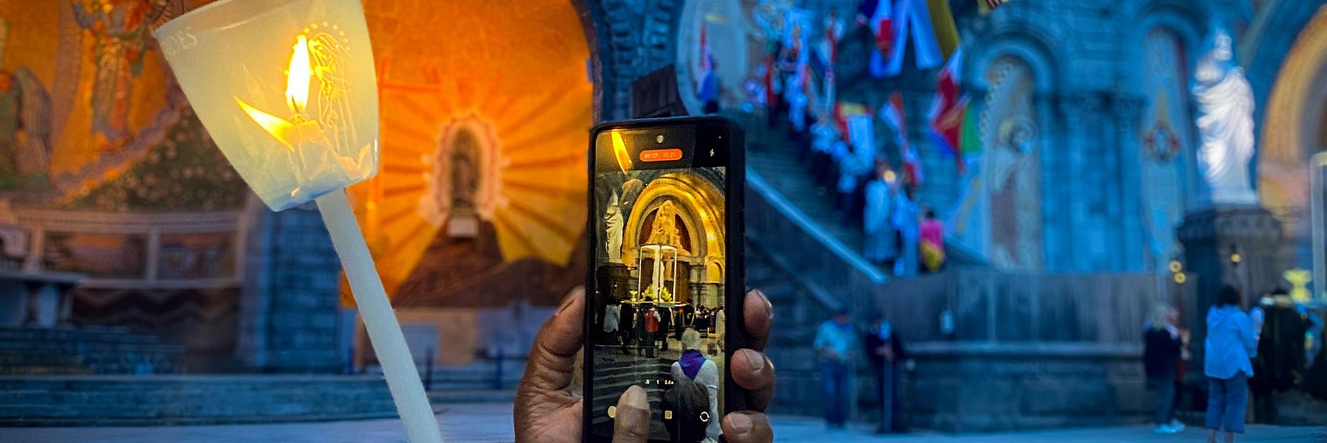 Eine Teilnehmerin macht ein Foto bei der Lichterprozession in Lourdes.