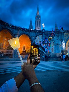 Eine Teilnehmerin macht ein Foto bei der Lichterprozession in Lourdes.